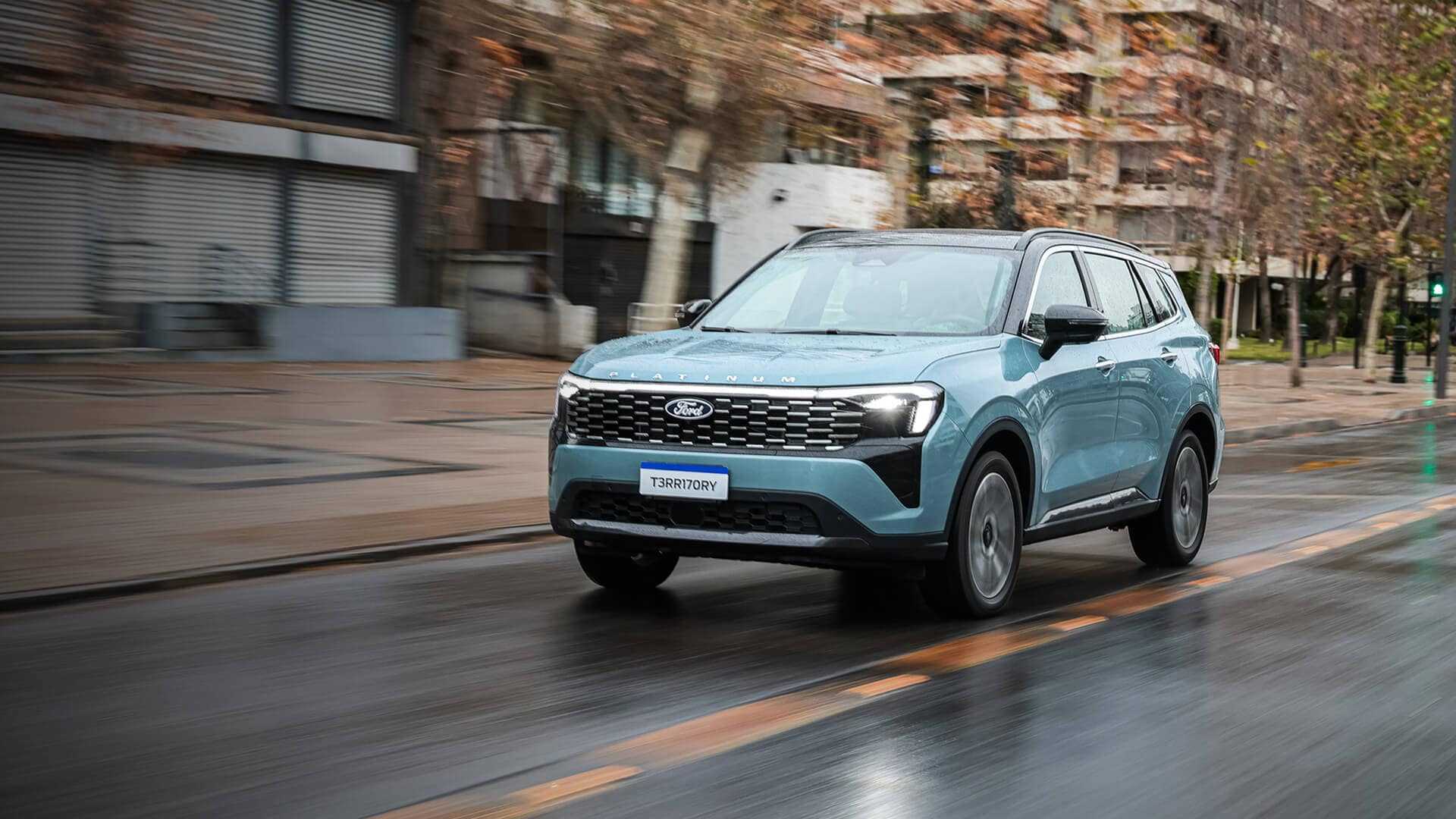 Ford Territory Platinum celeste en movimiento sobre una vía urbana mojada. Mostrar más líneas