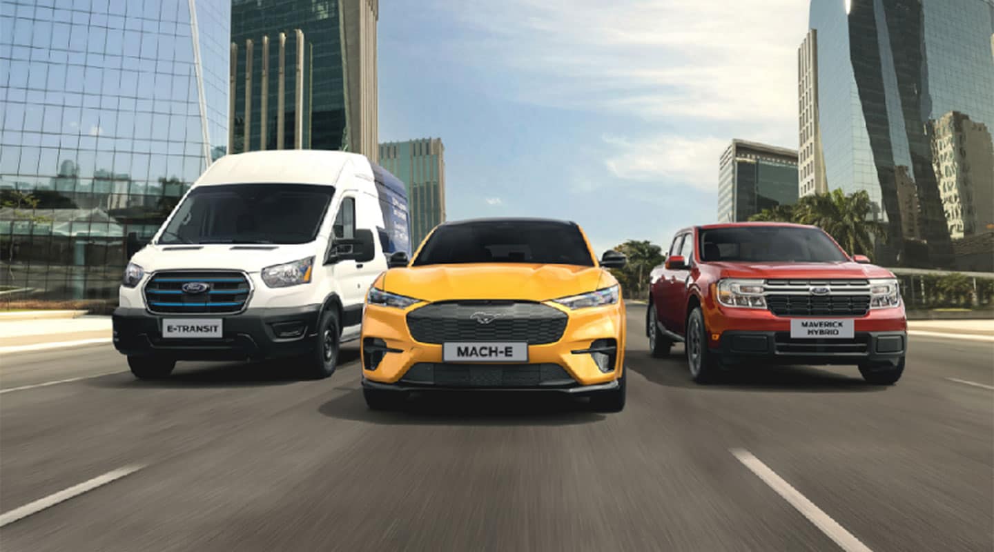 Una E-Transit, un Mustang Mach-E y una Maverick Hybrid circulan por un camino urbano