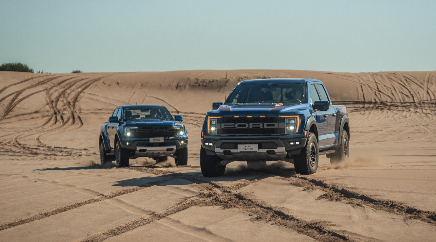Ford pick-up Ranger y Ford pick-up f-150 Raptor en un terreno arenoso 