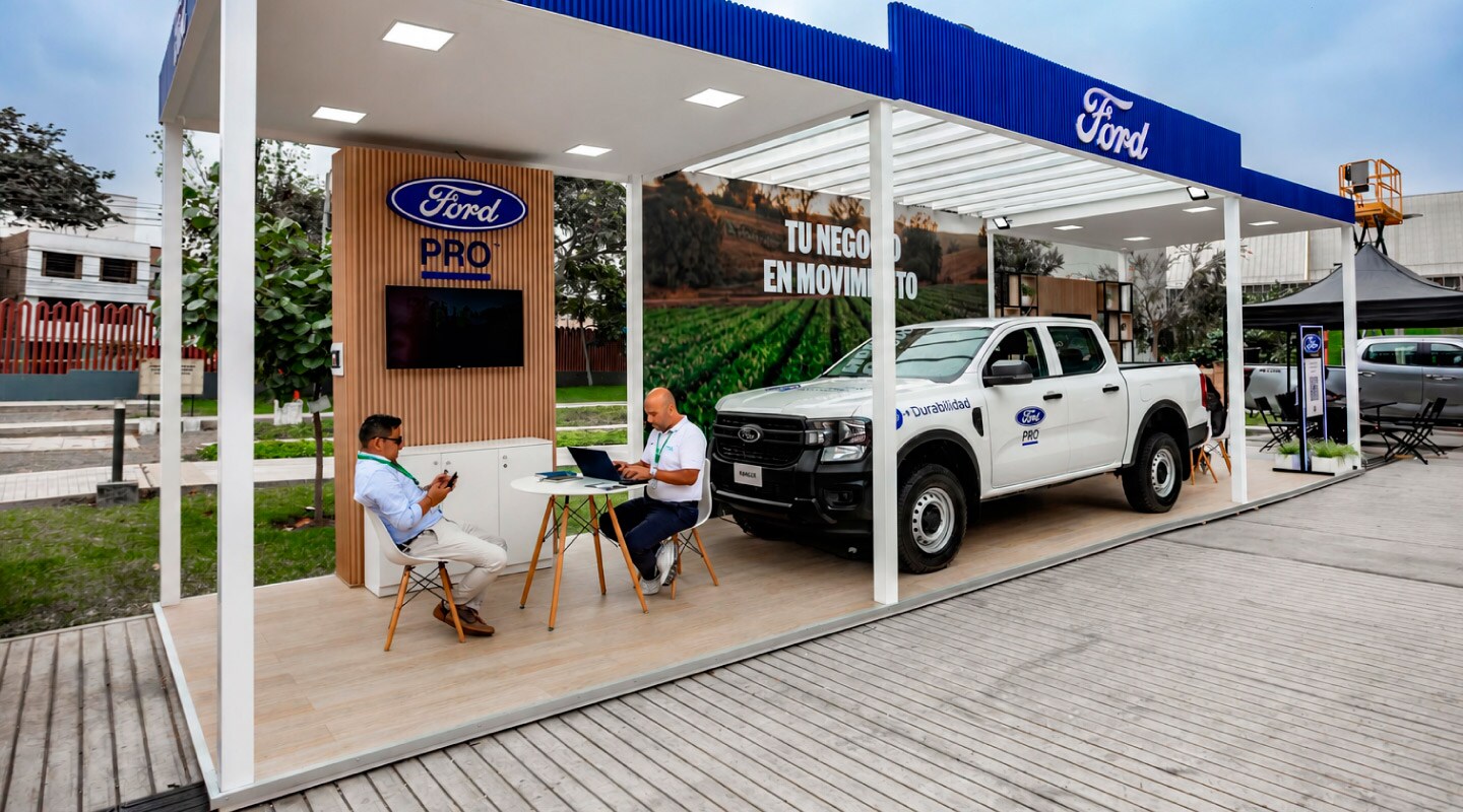 Estande da Ford Pro com uma Ford Ranger branca em exposição e visitantes em uma área de atendimento.