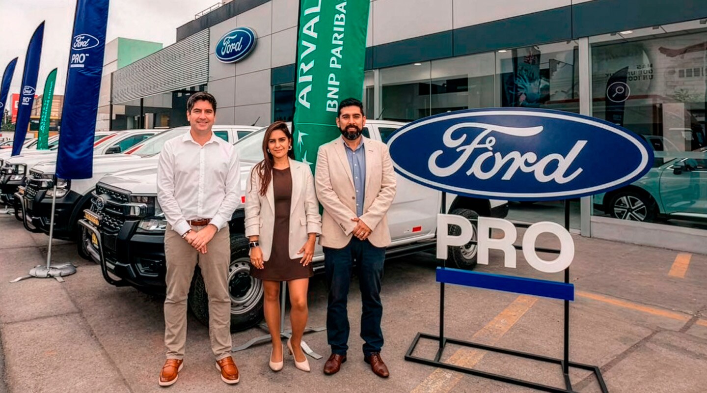Tres representantes posan frente a una concesionaria Ford PRO, junto a vehículos de flota.