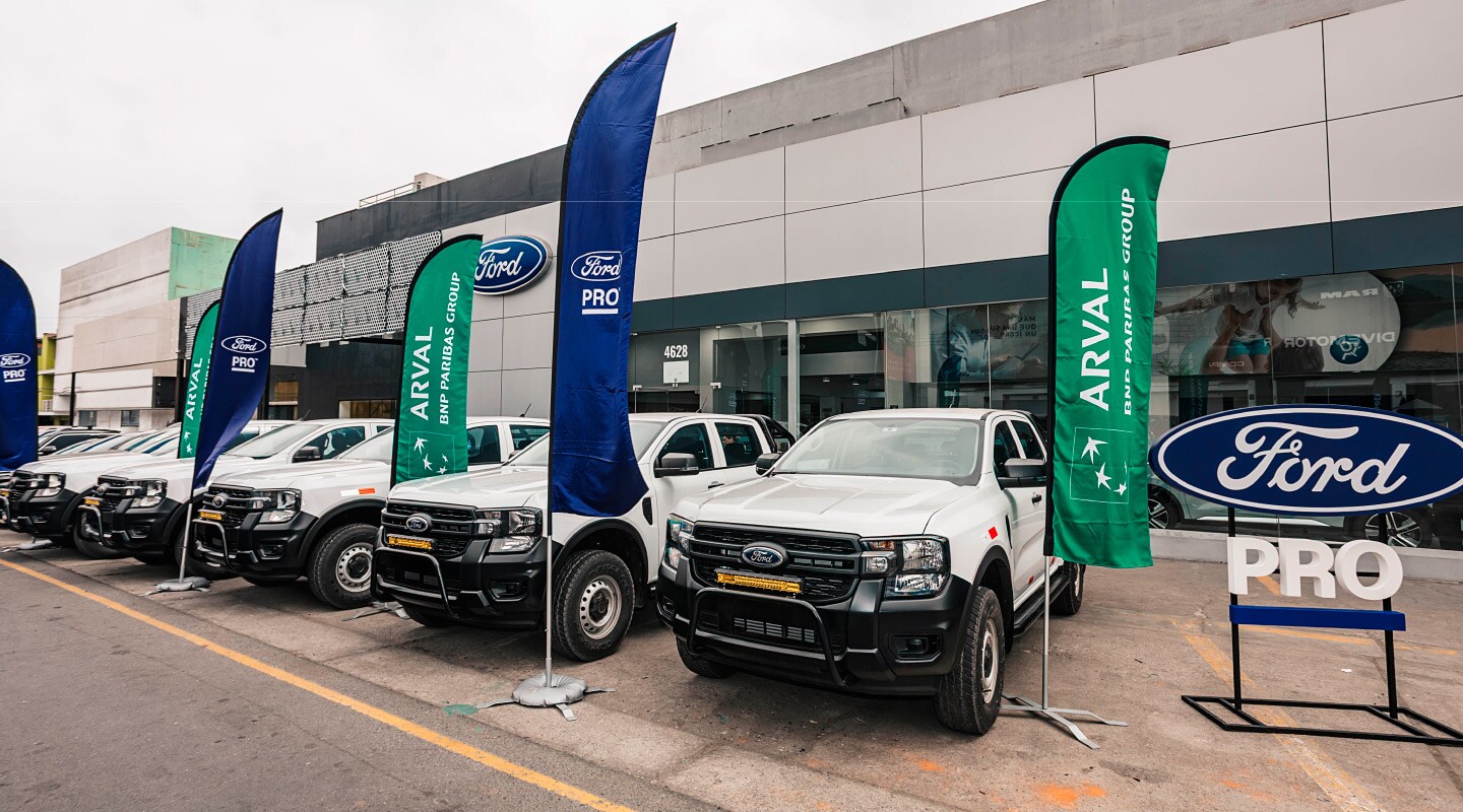 Flota de camionetas Ford Ranger blancas exhibida frente a una sede de Ford PRO.