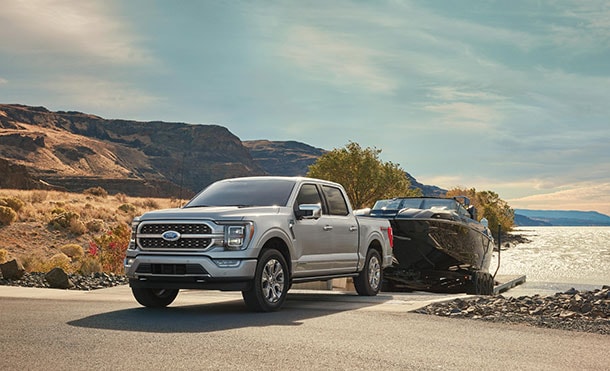 Ford F-150 Híbrida remolcando un bote desde un río. 