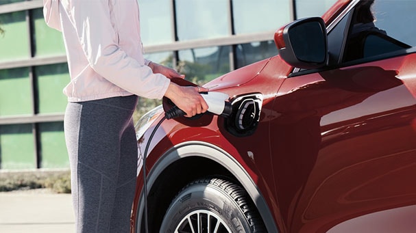 Mujer enchufando su vehículo Ford Escape Híbrido
